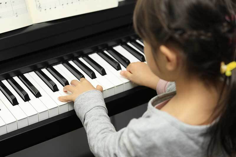 Young girl learning to play piano