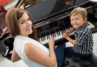 Woman teaching boy to play piano