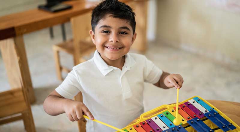 School ages boy playing child sized xylophone