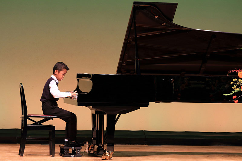 A young piano student plays at piano recital