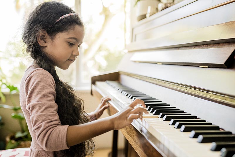 A young piano student practicing piano before her piano lesson