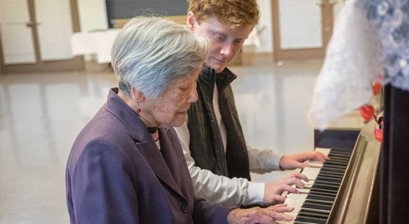 An older woman taking a piano music lesson with her instructor.