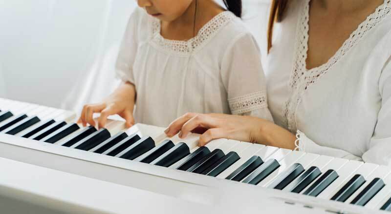 Closeup of young girl and woman each with one hand on keyboard.