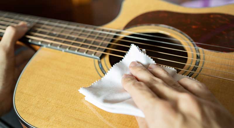 Close-up of someone cleaning a guitar with a soft cloth