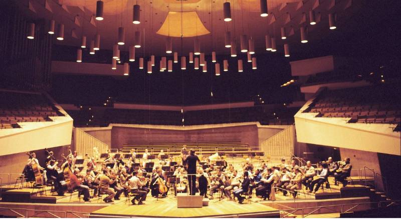 A school band is performing a concert in a large auditorium, showing musicians and their instruments in perfect harmony