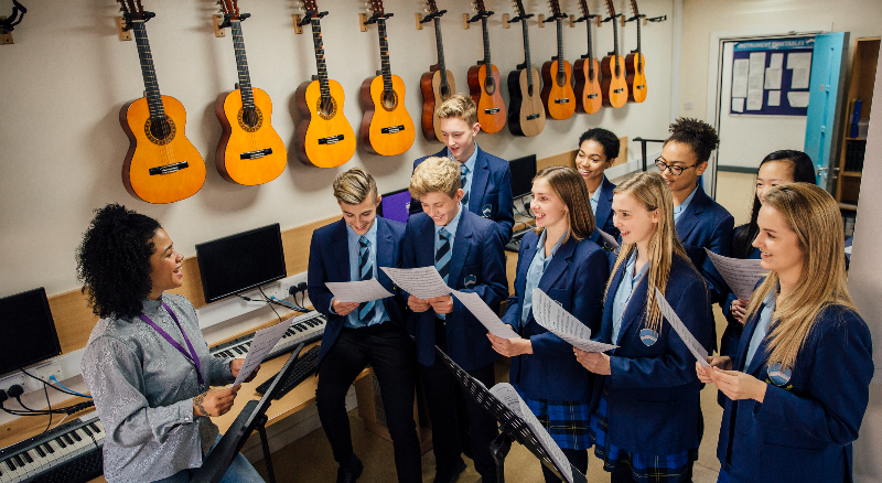 Choir students are rehearsing with their instructor in the school's music lab