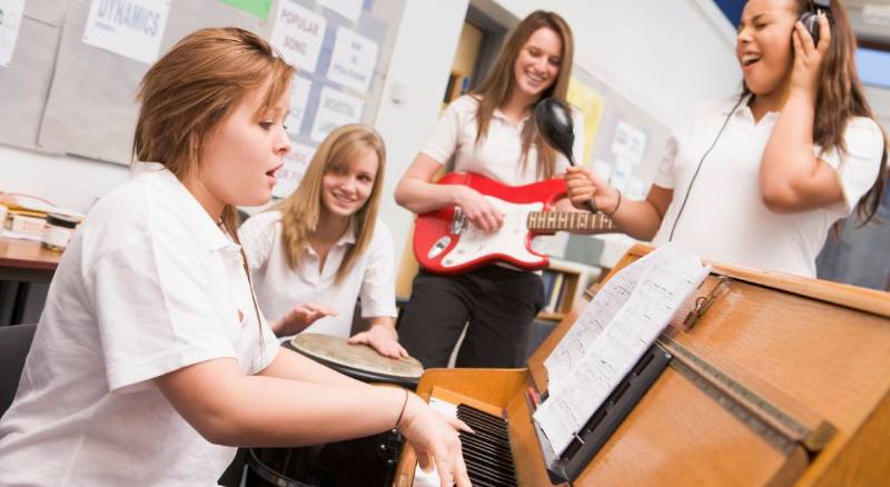 A small group of female musicians appear to be having fun while they rehearse