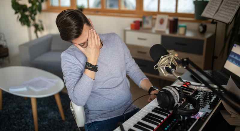 A man is sitting at his keyboard with his head in his hands expressing frustration