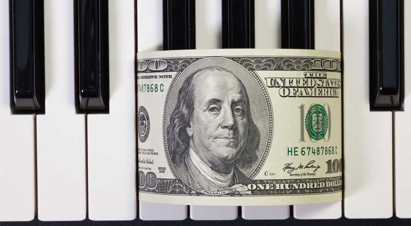 Piano keys with a hundred-dollar bill sitting on top