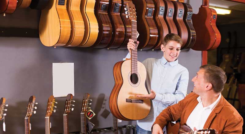 A young boy selecting a guitar with his father at a music studio