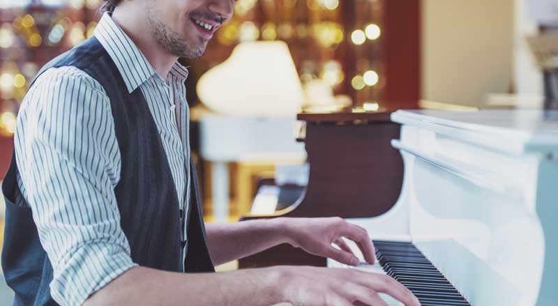 man playing white grand piano in music store