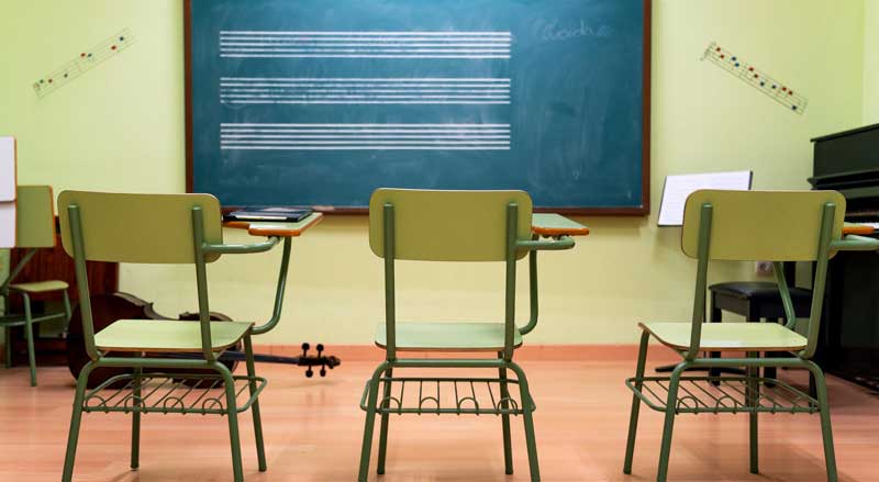 Music classroom with chairs facing a chalkboard marked with musical notes