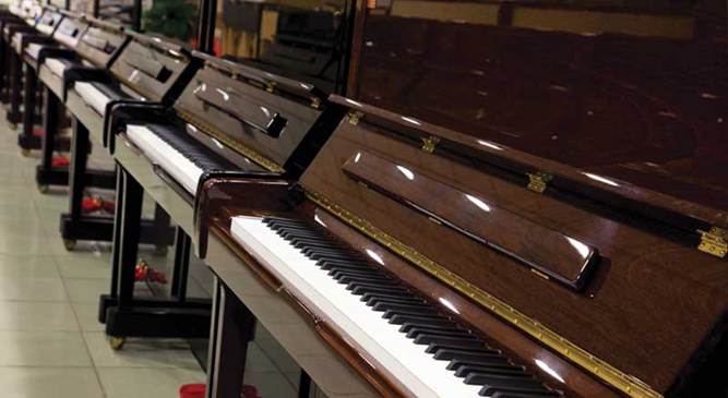 Close-up view of multiple upright pianos with glossy finishes, emphasizing keyboards and wood details